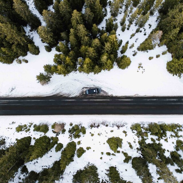 Aerial view of a Carado motorhome on a road between snow-covered forest
