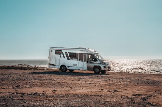 Carado motorhome in side view on a rocky coastal pitch by the sea