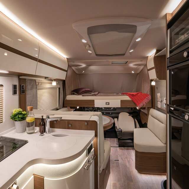 Lowerable front bed with red duvet and dark red decorative pillow in the HYMER B-Class MasterLine I 880