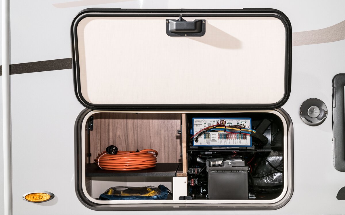 Exterior storage compartment with open flap for living area battery and electroblock on the HYMER Exsis-t