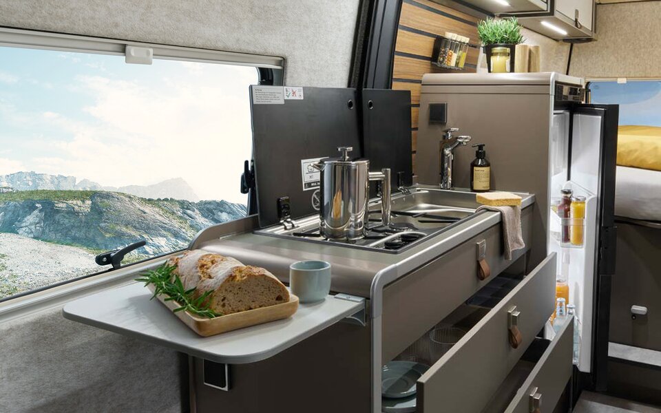 On the kitchen extension in the HYMER Grand Canyon S, there is bread. In the background, the kitchenette with stove, sink, and refrigerator is visible.