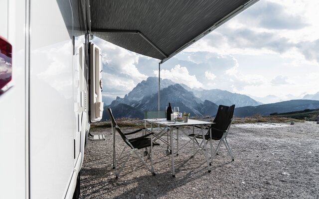 Camping furniture under the awning of the HYMER Exsis-i 580 Pure with a panoramic view of the Alps