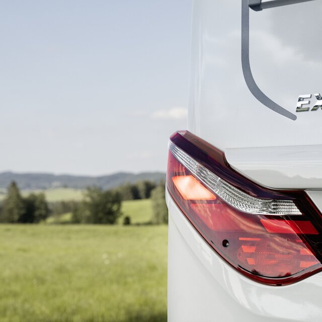 The rear light of the HYMER Exsis-t 580 Pure with a green meadow and trees in the background