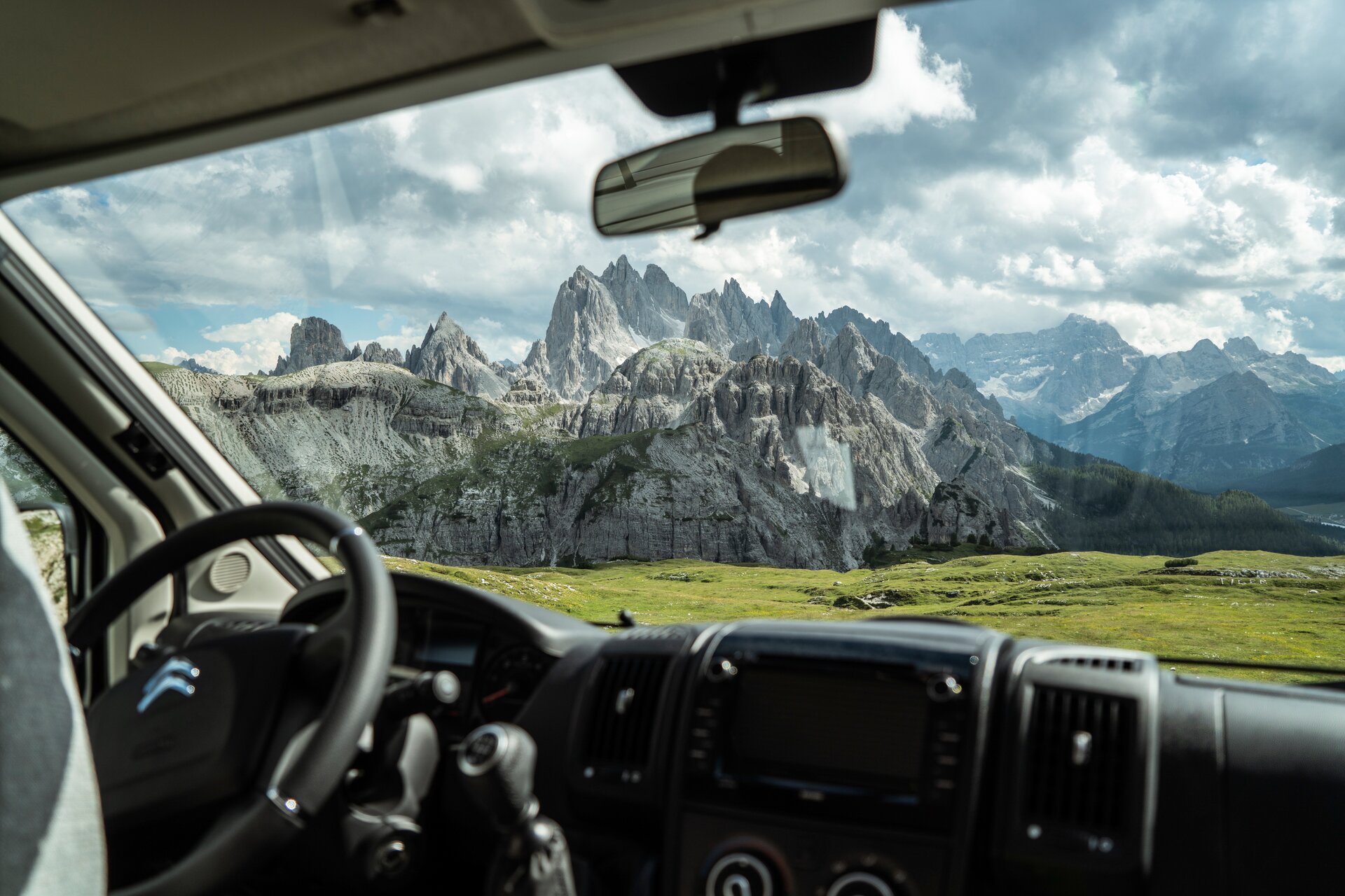 View from the driver's cab of the HYMER Exsis-t 580 Pure of the mountain range with a green meadow in front